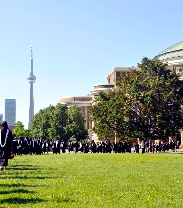 Toronto’s CN Tower is visible against a sunny sky as graduating students line up to enter Convocation Hall.